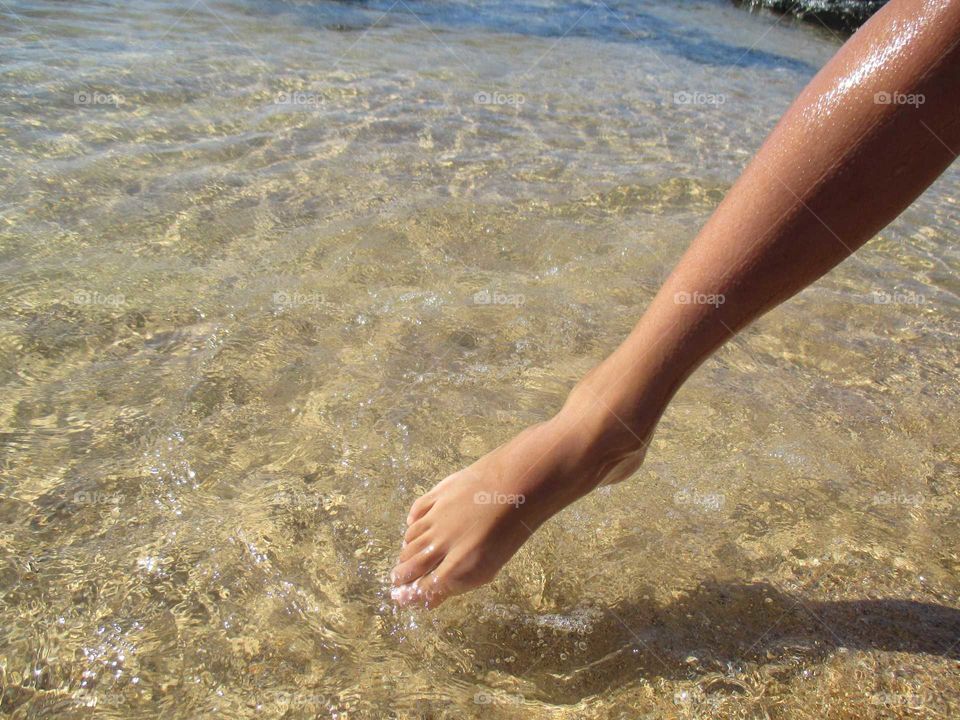 The memories of summer.. Child's foot touching the limpid ocean's water