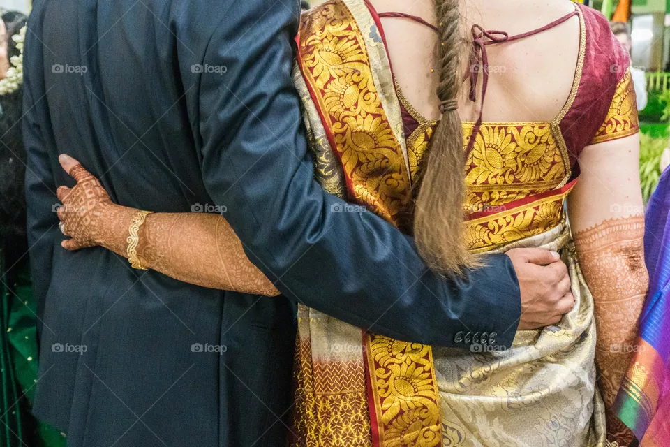 interracial bride and groom with arms around each other at a beautiful Indian wedding ceremony.