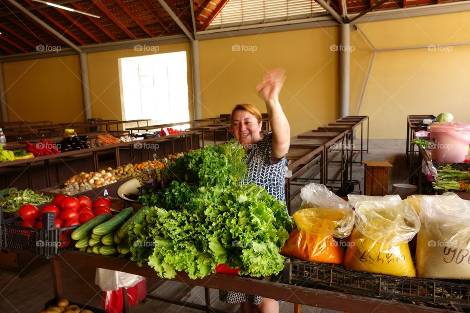 Vegetable vendor in Batumi. Female vegetable vendor waving hand as a greeting inside an indoors food market in Batumi, Georgia on 12 July 2014.