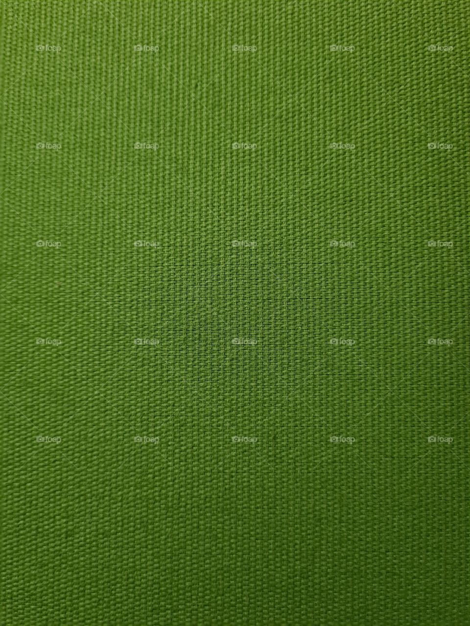 Dark green textile texture of fabric covering a bed's headboard seen from up close.