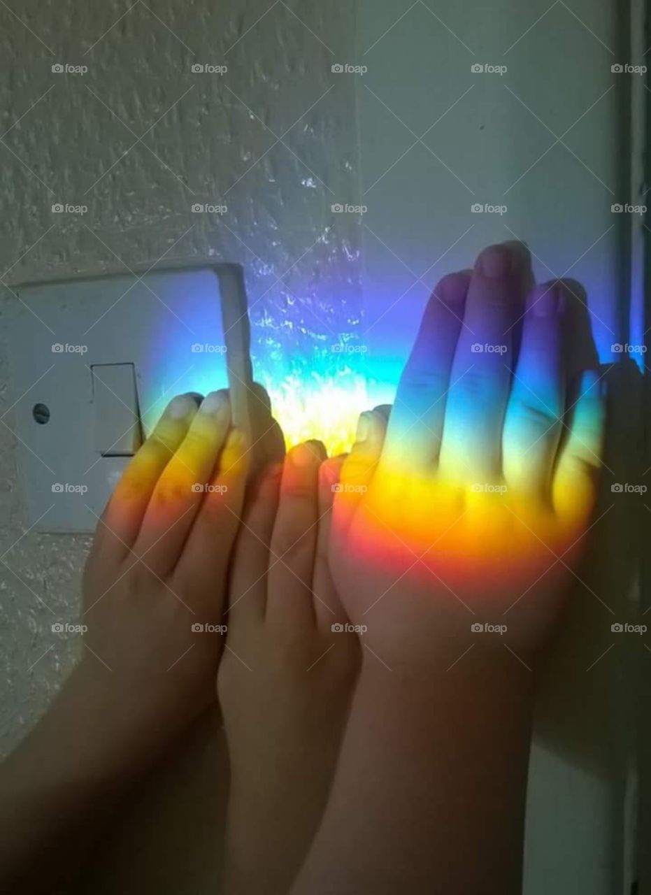 rainbow light on children's hands on wall