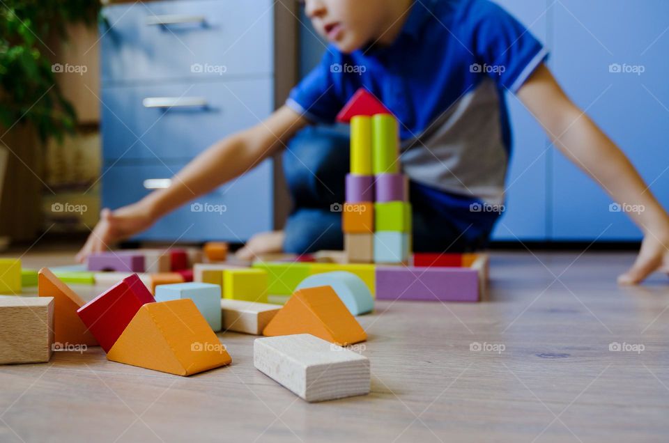 A little boy, a schoolboy, plays with wooden cubes at home, collects a constructor.