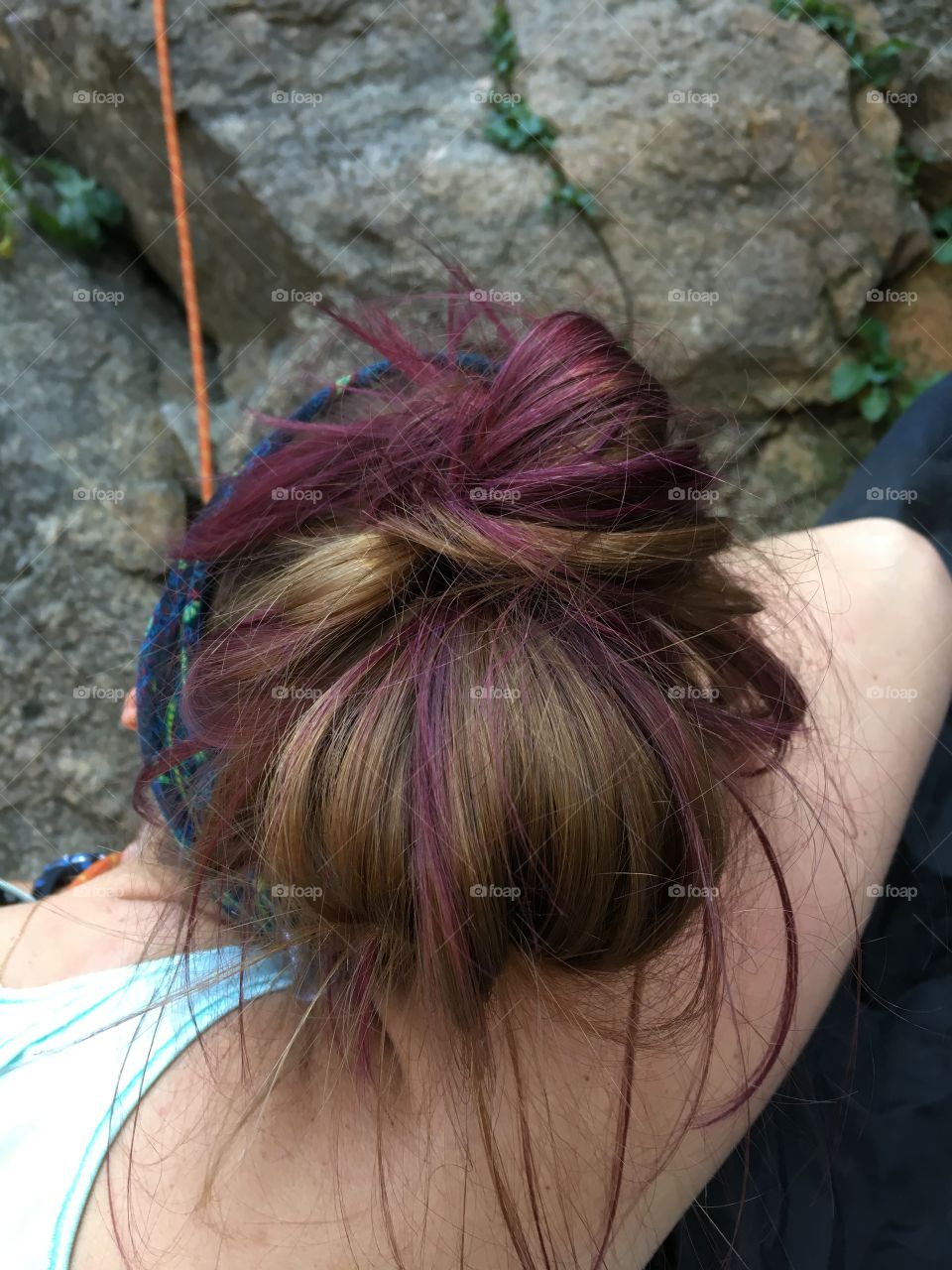 Dyed purple hair on a sport climber sitting outdoors on a mountain waiting to climb