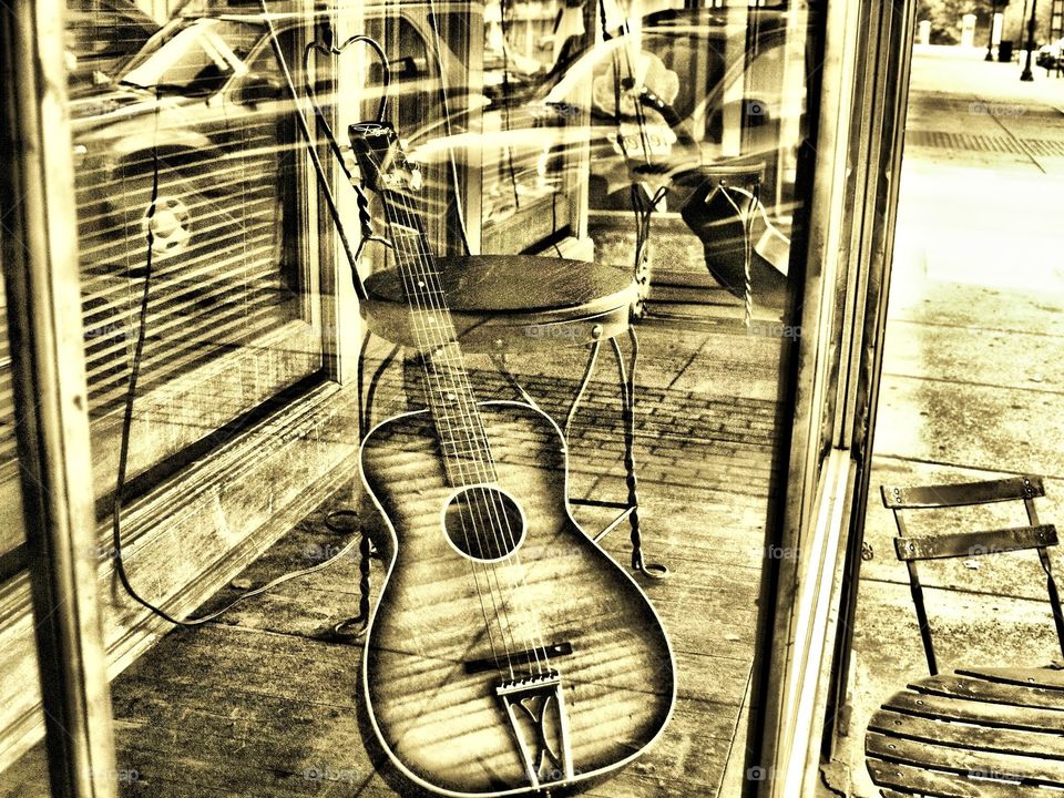 window display of guitar and chair in sepia