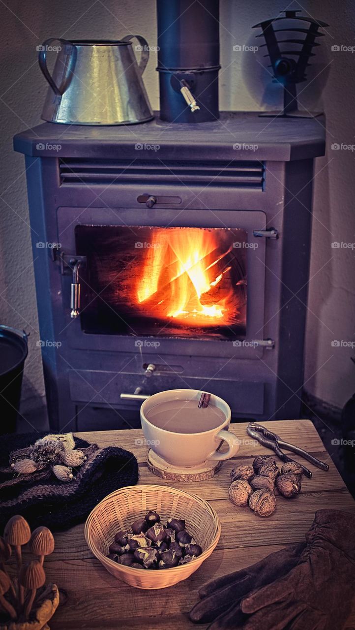 A table in front of a log burner with a warm winter beverage and seasonal nuts on it