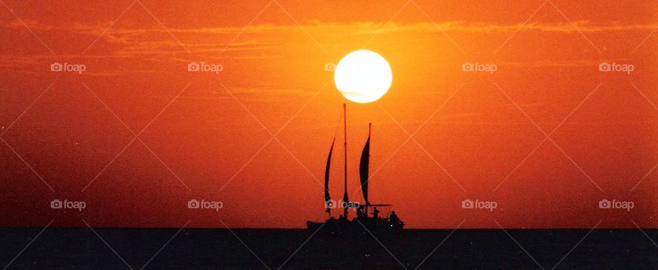 Silhouette of sailboat in sea at sunset
