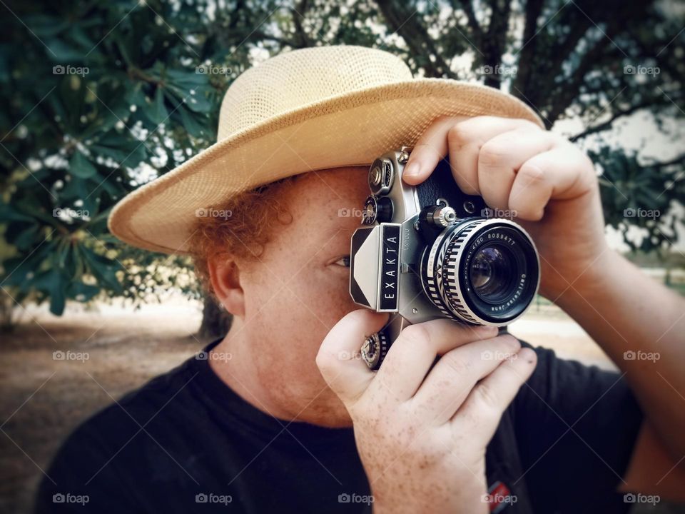 Man with a hat taking a photo