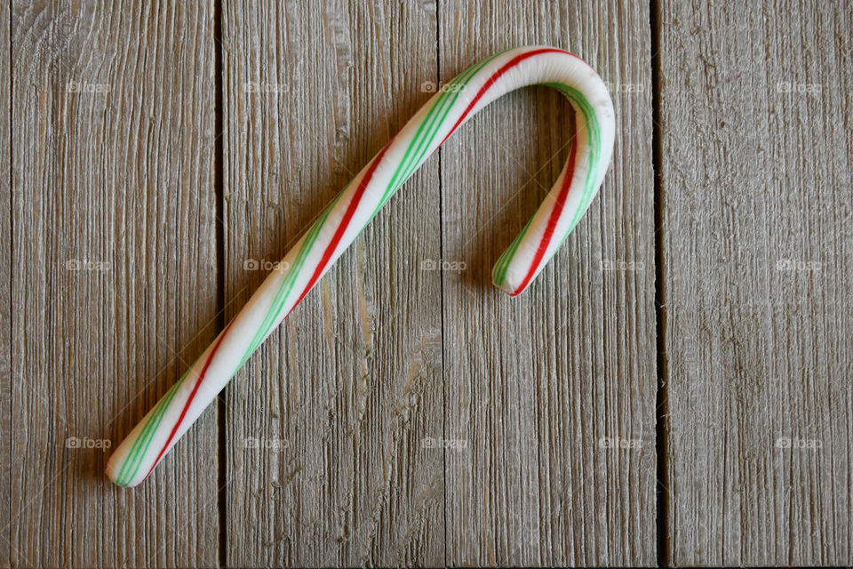 Green and red candy cane on wood background