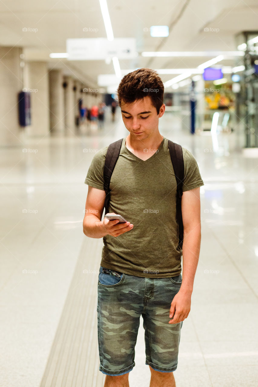 Young man standing in the railway station, planning a travel, travelling with backpack