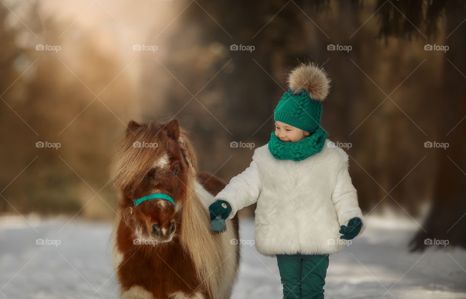 Little girl with pony at early spring day