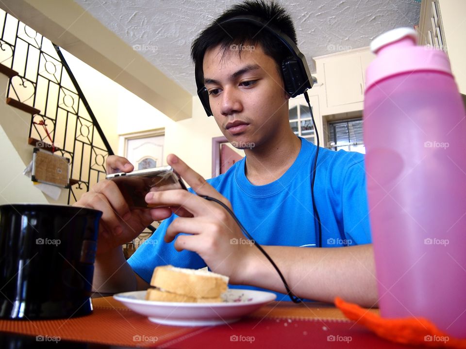 young teen eating snack while watching on a mobile device