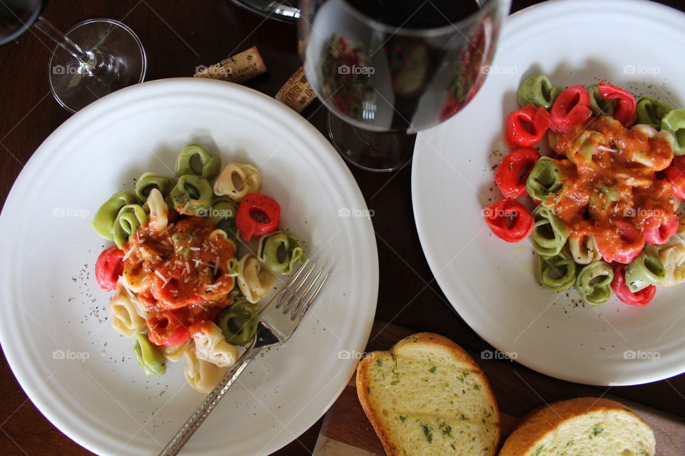 Italian inspired meal of tri-colored tortellini with red sauce and red wine.