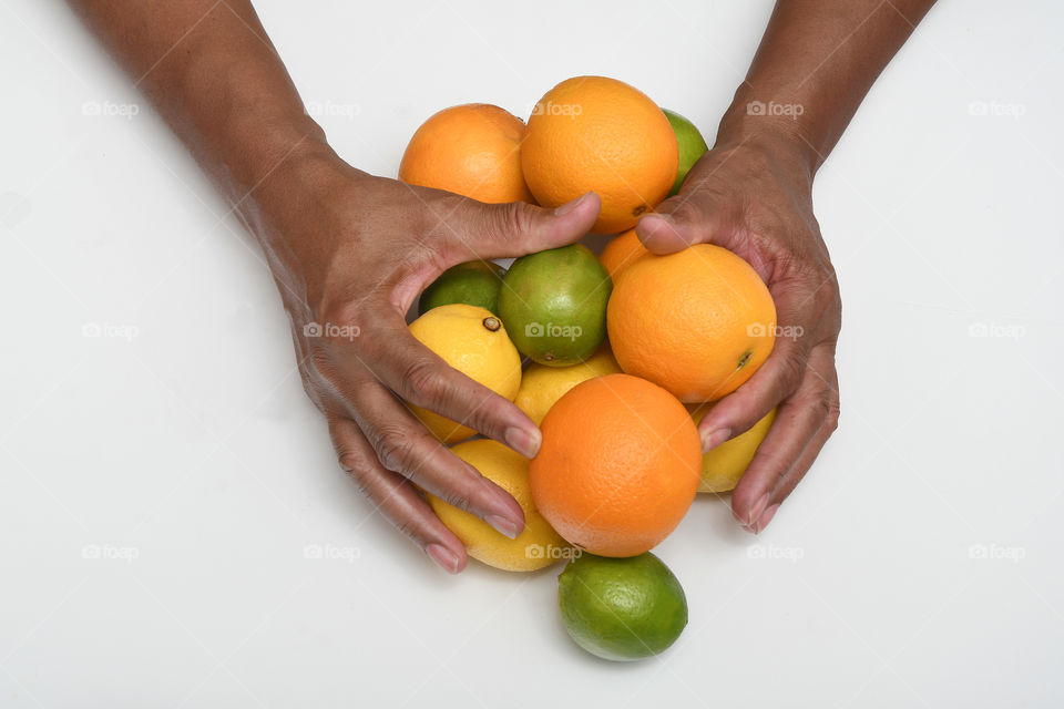 A man has his hands full with a citrus overload of delicious oranges, lemons, and limes.