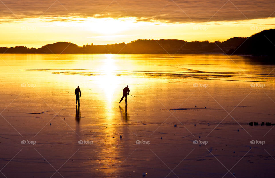 Skaters on frozen fjord.