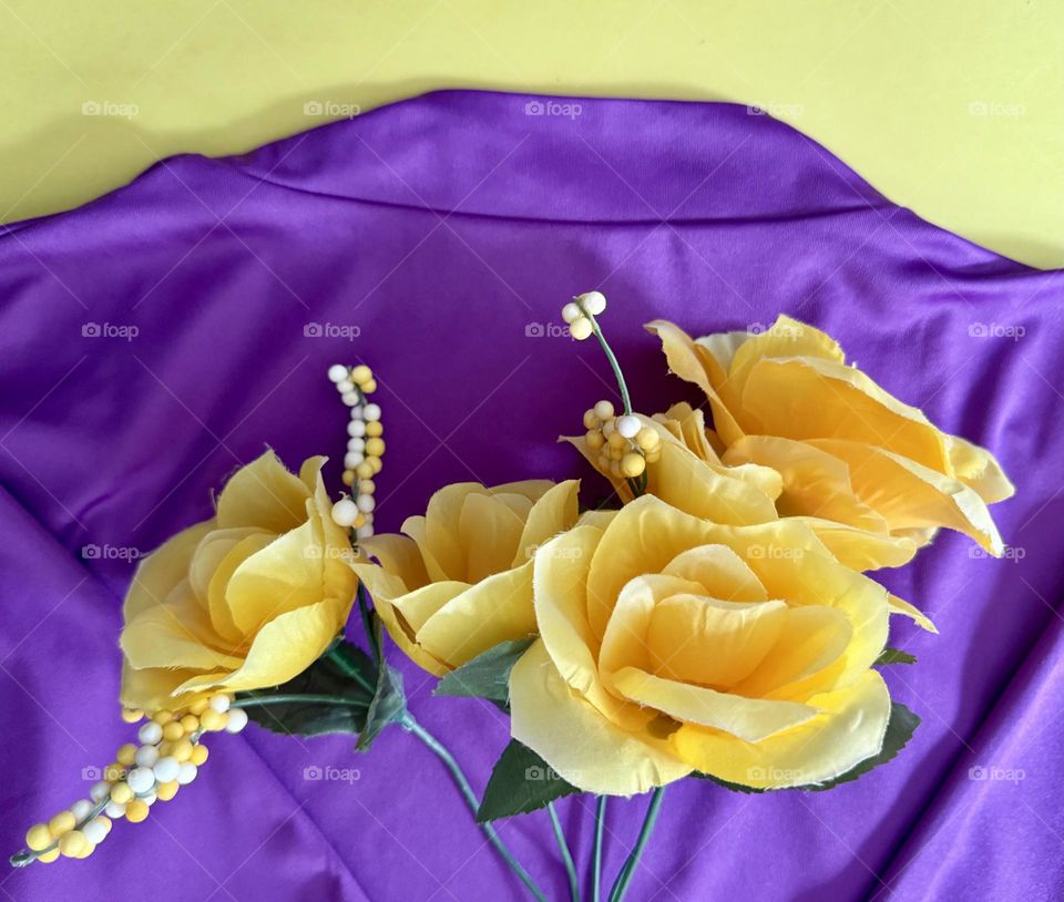 Yellow flowers against purple cloth on bright yellow background 