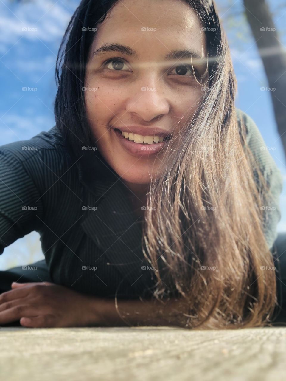 This picture has vivid colors and the sunshine highlights the strands of my hair. There is a warm joy to this picture. The wooden bench in contrast with the deep blue sky highlights the picture very well.