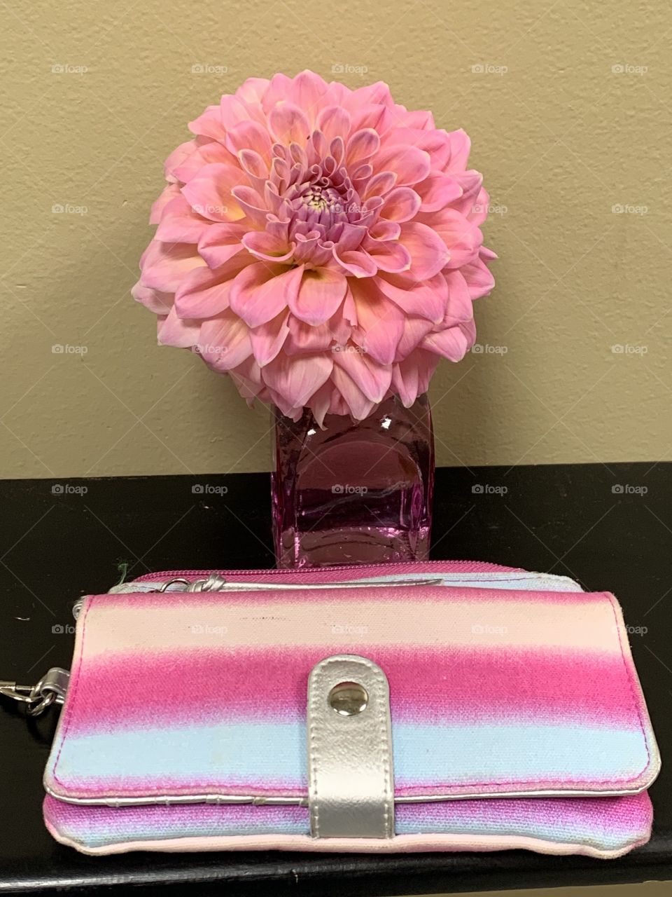 Pink flower in pink vase. Apricot, pink, purple, and light blue wallet bag with silver buckle.