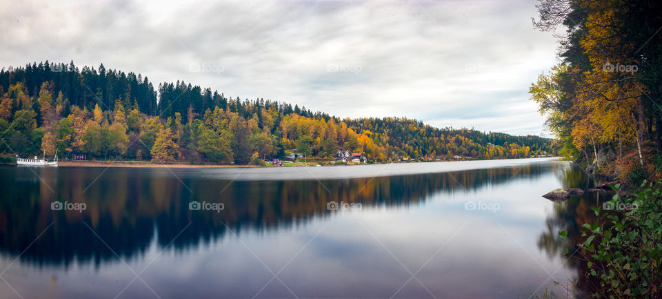 long exposure shot of the autumn foliage along a Swedish lakeside. Beautiful reflections on a glass smooth Lake