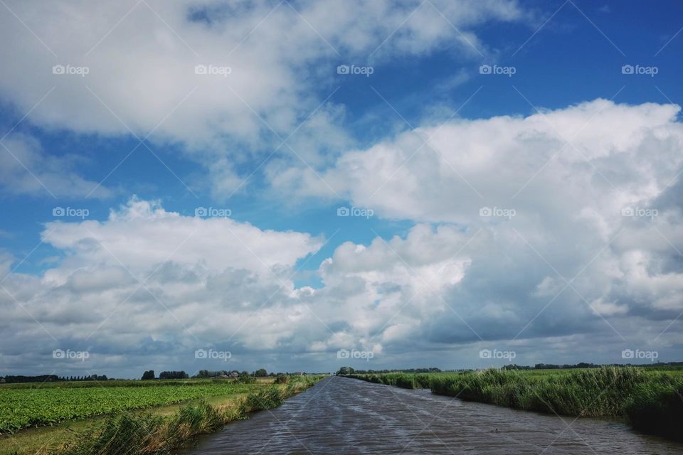 Dutch landscape, wide view, spacious with big clouds and blue skies, view from our boat, north of Netherlands