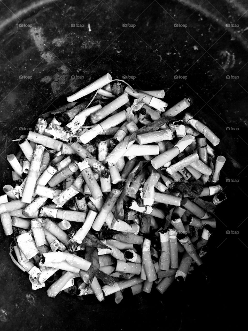 A bucket of cigarette butts. Monochrome enhancing its dull and deadly aspects.