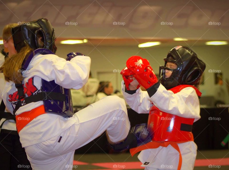 A girl throwing a kick during a sparring match. 