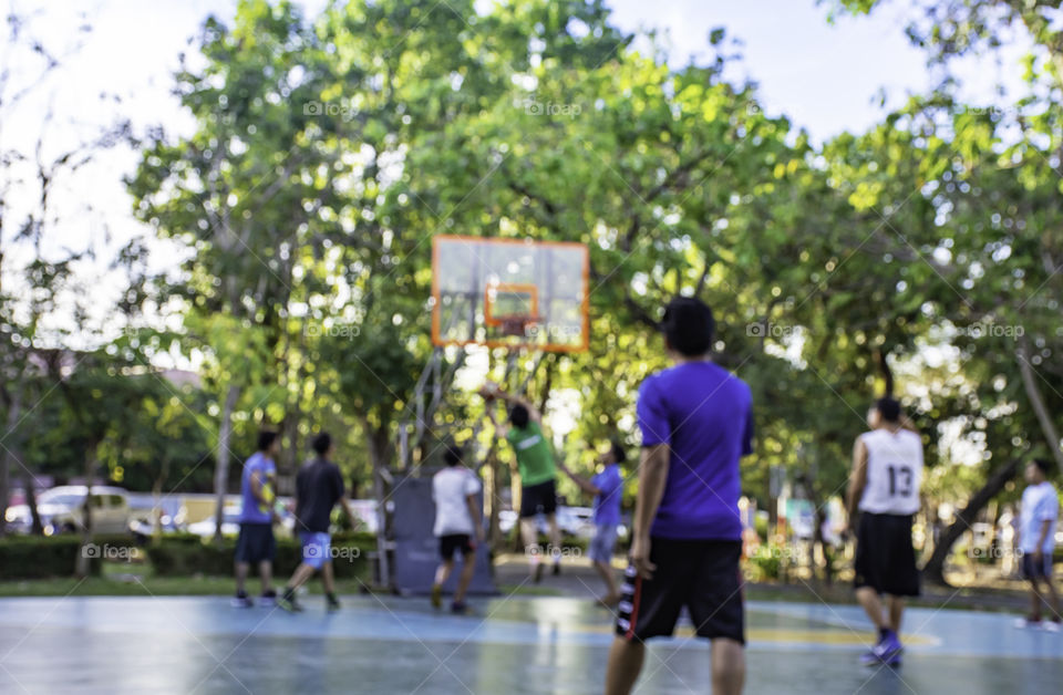 Blurry image of elderly men and teens playing basketball in the morning at BangYai Park , Nonthaburi in Thailand.