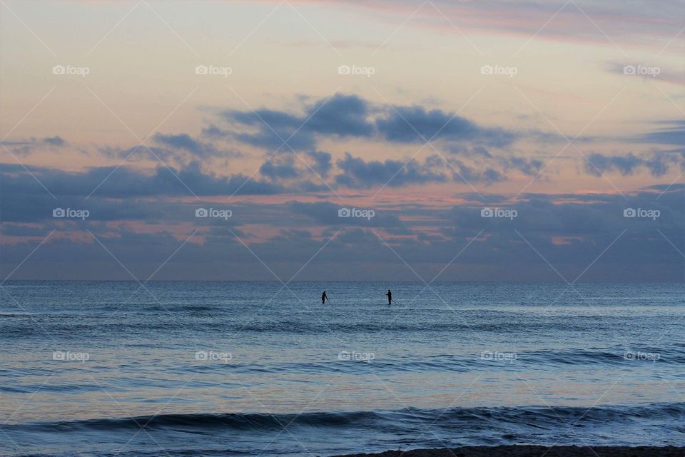 Two guys out on their paddle boards at Sunrise under the pastel sky at Burleigh Heads