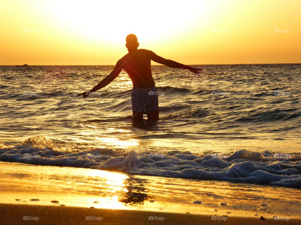A Young Man in the Water at Sunset