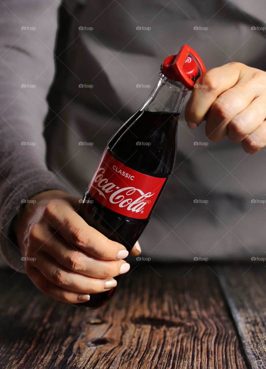 Female hands open a bottle of coca cola