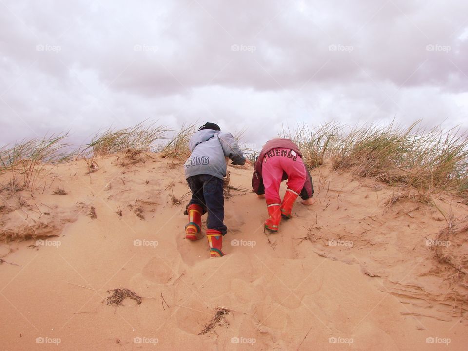 Climbing. Two children climbs the sand hills at the beach