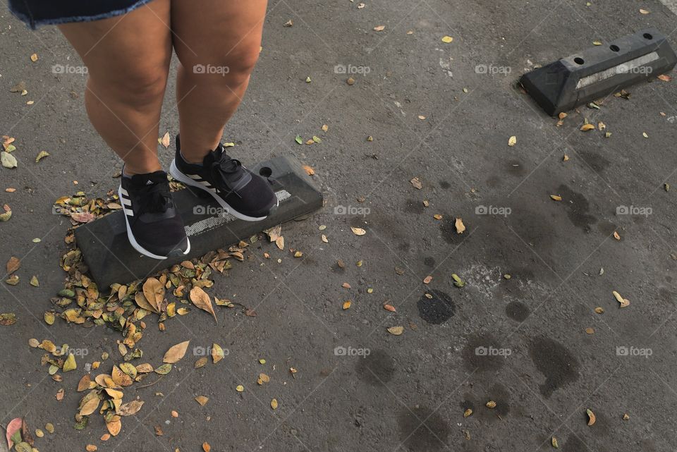 Dried yellow leaves fallen on the asphalt in a parking lot of vehicles