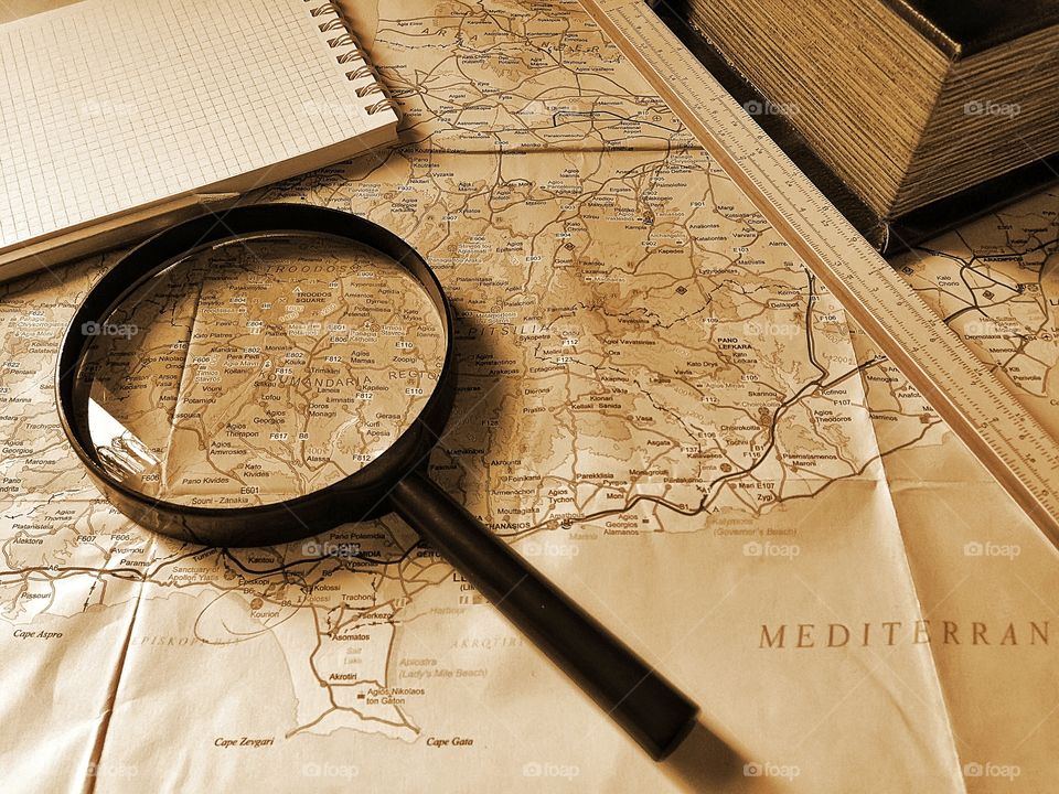 Travel items flat lay on a map in monochrome sepia colors