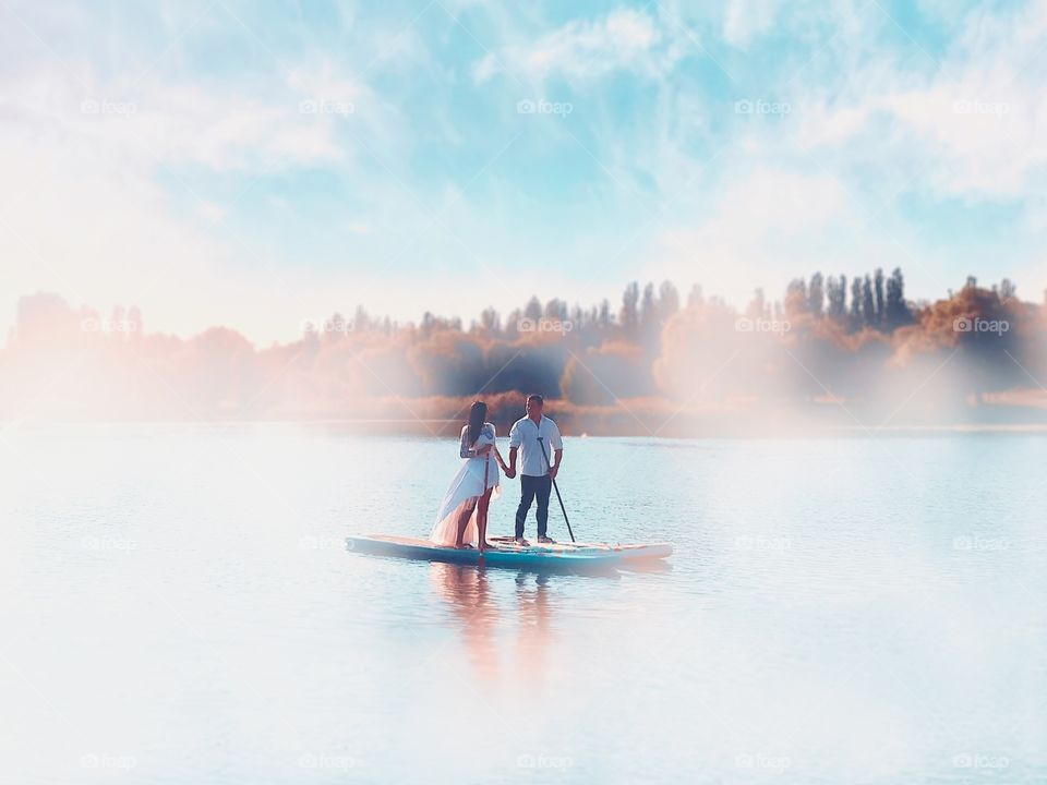 Couple in love standing on a paddle board 