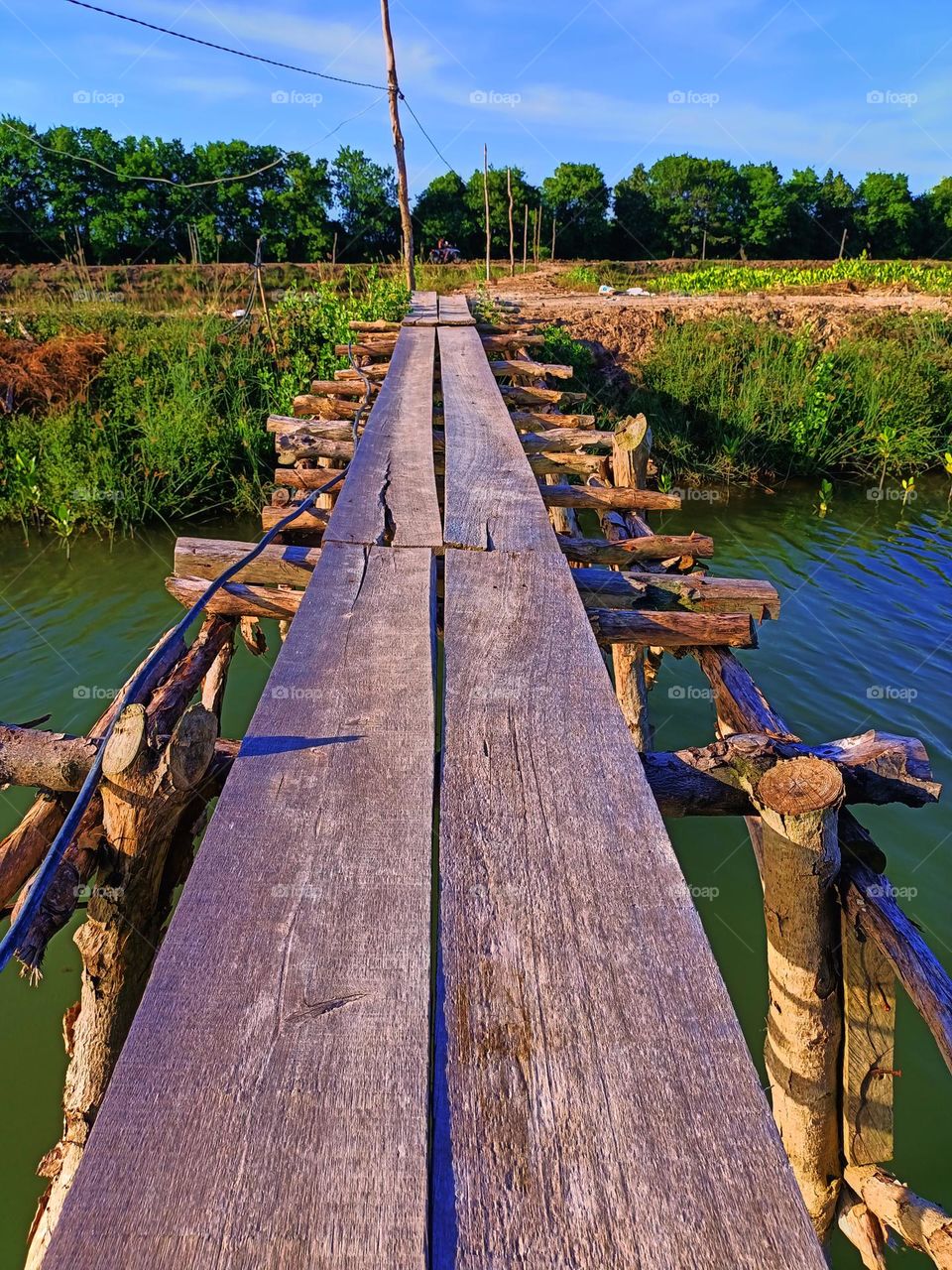 Simple old wooden bridge or pedestrian footbridge across a coastal river