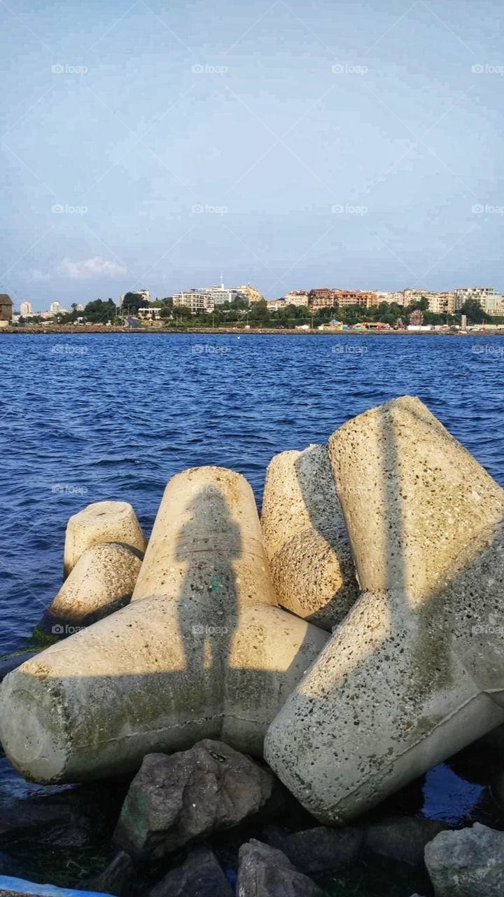 Sunset at sea silhouette of a girl on a breakwater