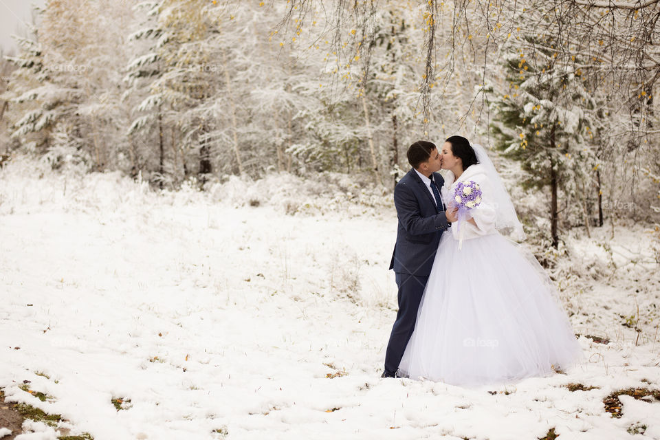 Newly wed couple kissing on snowy landscape