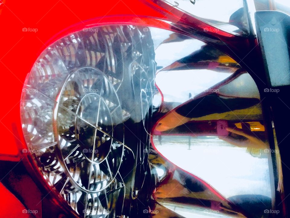 A surreal looking collage of car pieces resulted when I took a photograph of the headlights of a parked red sportscar through its rear view mirror. The picture was taken in 2019 in Long Island City, Queens. Hypnotic Productions