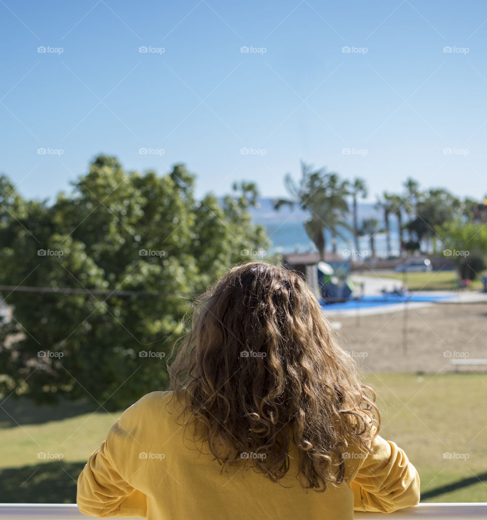 Blonde girl watching the beach from her balcony