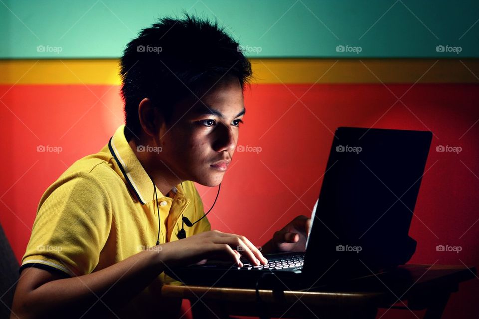 young asian teen working on a laptop computer