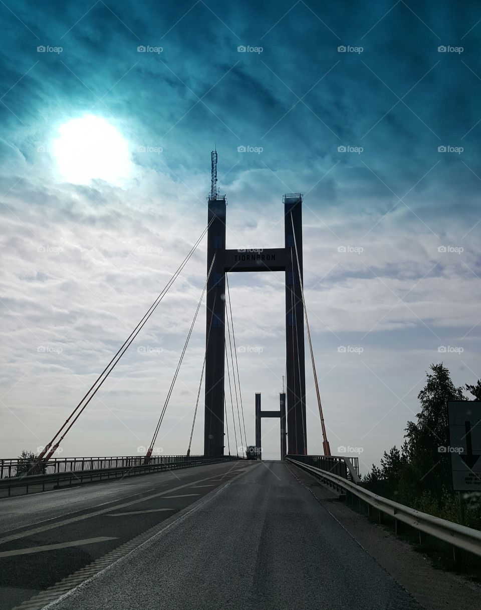 Suspension bridge against cloudy sky