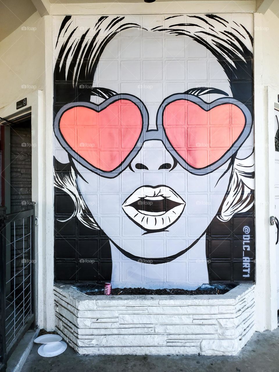 Visual street art: Black and white portrait of a woman with pink heart shape shades by artist @DLC_ART1