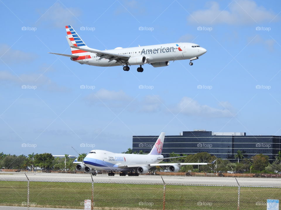 Plane spotting located at Miami International Airport watching a Boeing 737 landing while a Boeing 747 from Air China Cargo waits in the background 