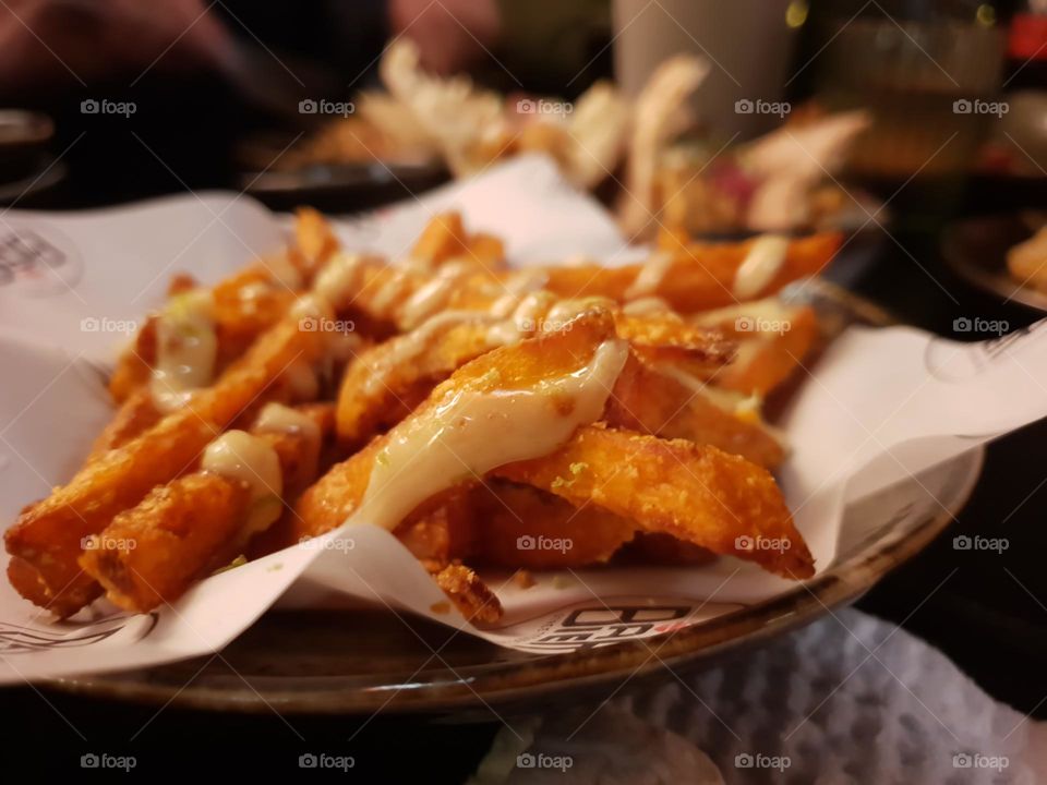 A portrait of sweet potato fries with a sauce based on greek yoghurt on a plate in a restaurant.