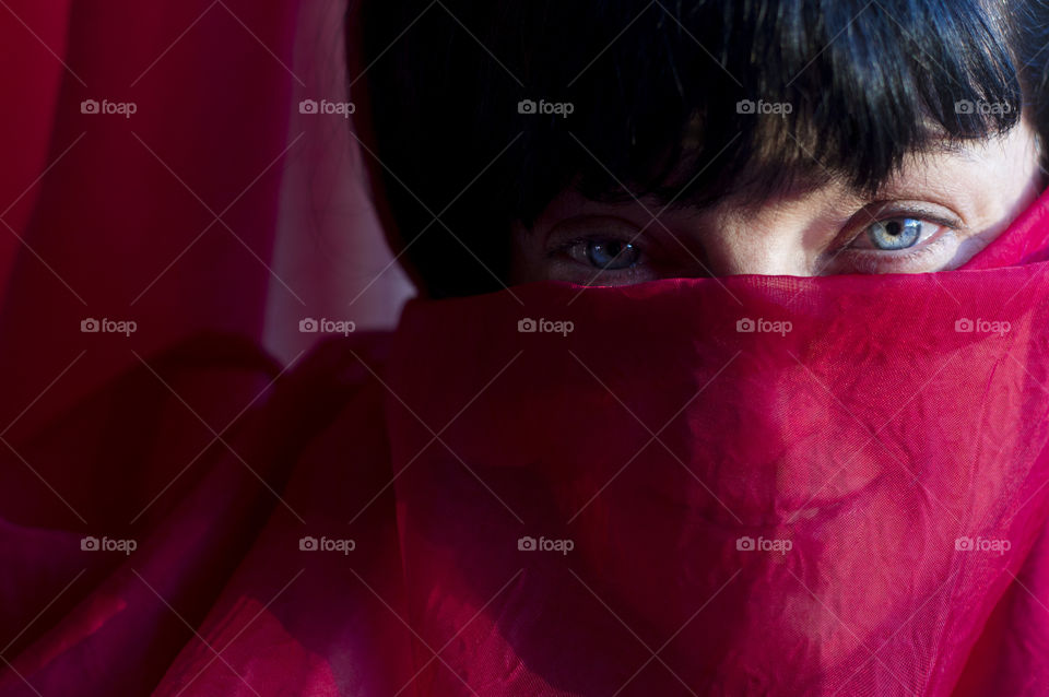 A woman with blue eyes behind red veil