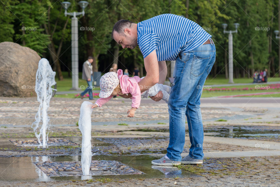 dad and kid are playing with fountain