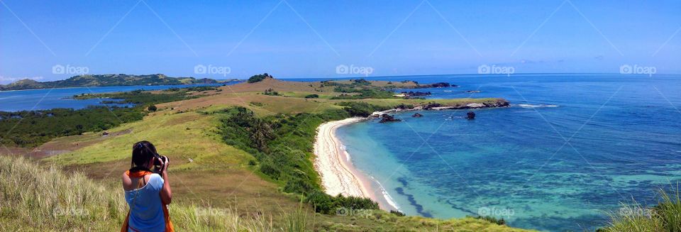 lady uaing dslr camera to capture beautiful scenic view of the beach