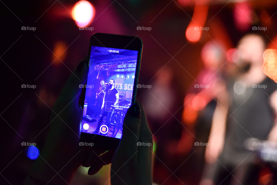 Person recording music concert using cell phone