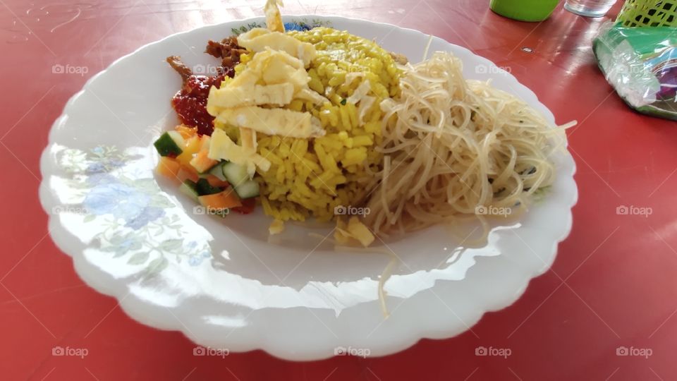 Nasi Kuning, or Nasi Kunyit, popular Indonesian cuisine with coconut milk and turmeric. The rice looks like a pile of gold, often served at parties, as a symbol of good fortune, wealth and dignity.