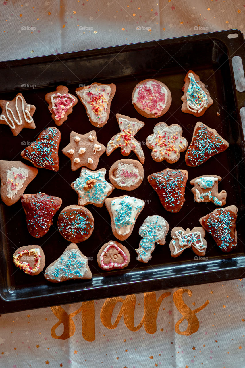 Christmas gingerbread cookies in many shapes decorated with colorful frosting, sprinkle, icing, chocolate coating, toppers, put on tray