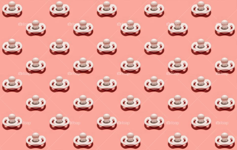 White baby pacifier pattern on pink background
